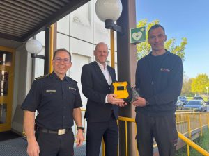 Feuerwehrkommandant Sebastian Fischer, Erster Bürgermeister Dirk Büscher und Notfallsanitäter sowie Praxisanleiter Stephan Bürkle (von links) stellen den neuen, öffentlich zugänglichen AED an der Hauptfeuerwache vor.
