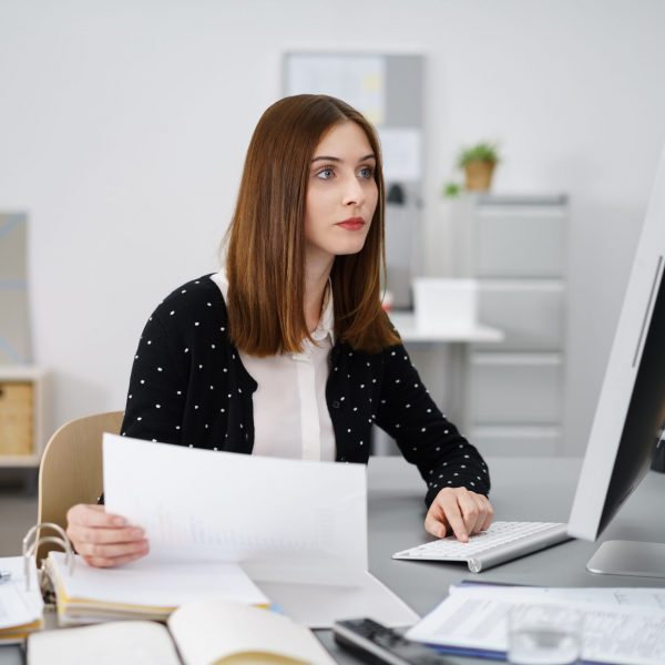 frau bearbeitet unterlagen am arbeitsplatz