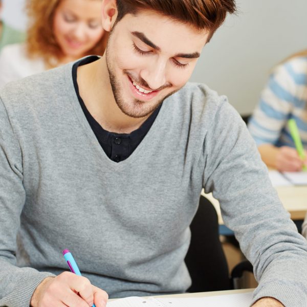 Junger Mann schreibt eine Klausur in der Universität